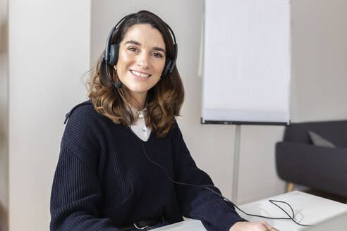 Smiling businesswoman wearing headset in office - XLGF03309