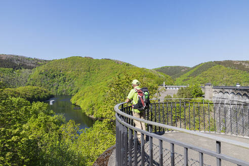 Deutschland, Nordrhein-Westfalen, Älterer Wanderer blickt von der Aussichtsplattform auf den Rursee - GWF07754