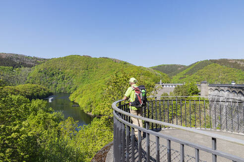 Germany, North Rhine Westphalia, Senior hiker looking toward Rursee lake from viewing platform - GWF07754