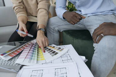 Geschäftsfrau bei der Auswahl eines Farbtons anhand eines Musters mit einem Kollegen im Büro - OSF01415