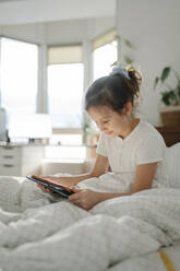Mädchen benutzt Tablet-Computer im Schlafzimmer zu Hause - SSYF00120