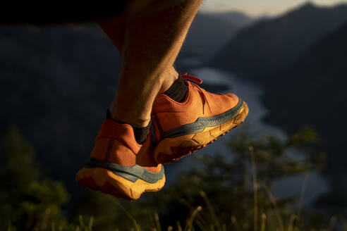 Mann mit gekreuzten Beinen auf einem Berg sitzend bei Sonnenuntergang - MALF00433