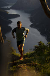 Sportler joggt bei Sonnenuntergang auf einem Berg - MALF00434