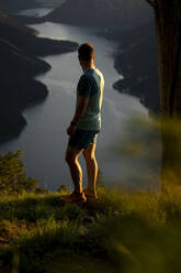 Sportler bewundert den See auf einem Berg stehend bei Sonnenuntergang - MALF00436