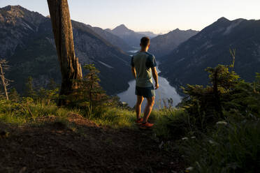 Sportler bewundert See stehend auf Berg bei Sonnenuntergang - MALF00437