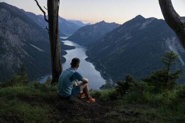 Sportler bewundert Bergkette und See bei Sonnenuntergang - MALF00439
