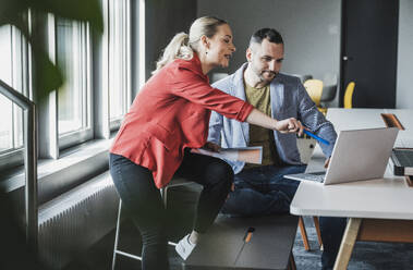 Businesswoman pointing at laptop by colleague at office - UUF28367