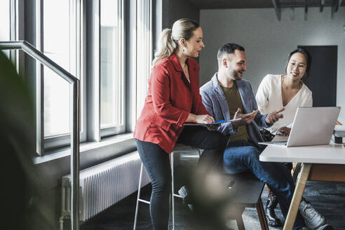 Gemischtrassige Geschäftskollegen diskutieren gemeinsam im Büro - UUF28369