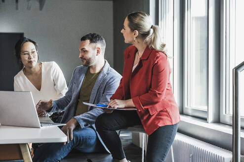 Geschäftskollegen, die in einer Besprechung im Büro miteinander diskutieren - UUF28370