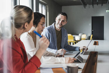 Businessman discussing with colleagues in meeting at office - UUF28382