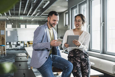 Business colleagues with wireless technologies sitting at desk in office - UUF28394