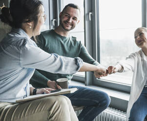 Glückliche Geschäftskollegen, die sich im Büro gegenseitig die Fäuste stoßen - UUF28422