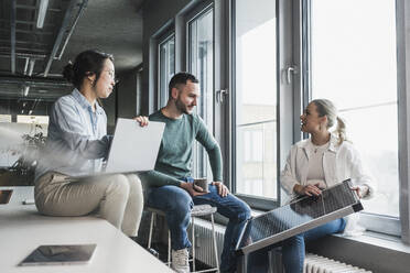 Businesswoman explaining solar panel to multiracial colleagues in meeting at office - UUF28429