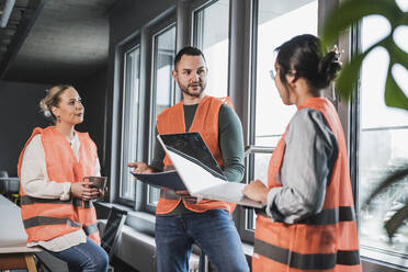 Mann in reflektierender Kleidung plant Strategie mit Kollegen in einer Besprechung im Büro - UUF28451