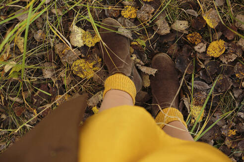 Woman wearing boots standing on fallen leaves - LLUF01060