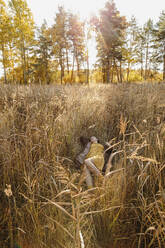 Woman lying amidst dry grass on field - LLUF01063