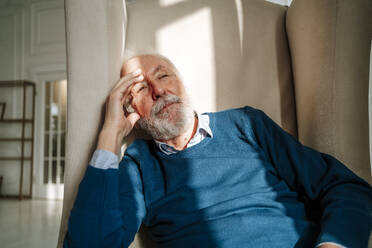 Nachdenklicher älterer Mann, der zu Hause auf einem Sessel sitzt - MDOF00817