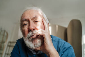 Nachdenklicher älterer Mann mit grauem Haar sitzt zu Hause - MDOF00820