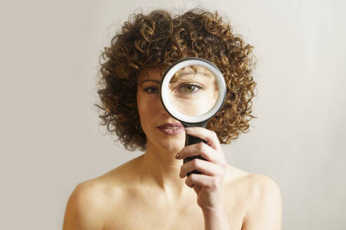 Woman with magnifying glass against white background - JSMF02734