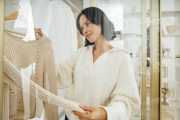 Woman choosing clothes seen through glass at home - VPIF07889