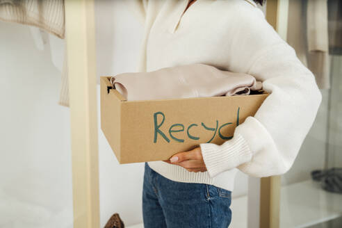 Junge Frau mit Kleidung in einer Recyclingbox - VPIF07906