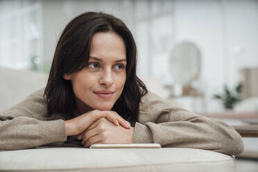 Thoughtful woman lying on sofa at home - VPIF07949