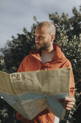 Man reading map standing in nature - DMGF01075