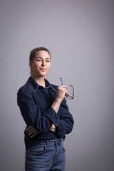 Lächelnde Geschäftsfrau mit Brille vor einem farbigen Hintergrund - MIKF00121