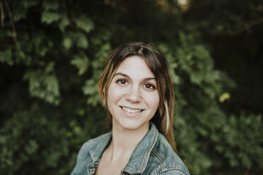 Smiling young woman in front of plants - GMLF01318