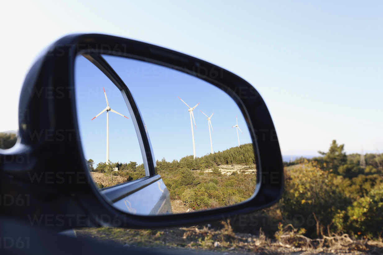 Windräder spiegeln sich im Seitenspiegel eines Autos, lizenzfreies
