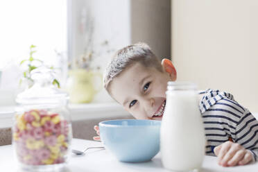 Glücklicher Junge mit Frühstück auf dem Tisch zu Hause - ONAF00429