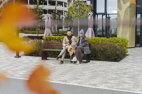 Mann und Frau sitzen mit ihrem Sohn auf einer Bank am Fußweg - SEAF01814