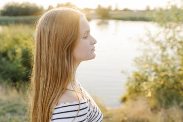 Thoughtful girl with blond hair in front of lake - SSYF00142