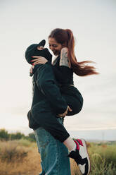 Young couple in love hugging on the street during sunset - CAVF96601