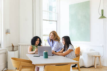 Businesswoman discussing strategy with colleagues over laptop - CAVF96633