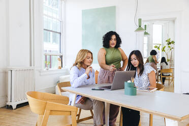 Young businesswoman discussing strategy with colleagues in meeting - CAVF96638