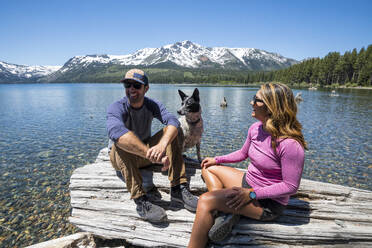 A couple relaxes with their dog on the shoreline of Fallen Leaf Lake. - CAVF96650