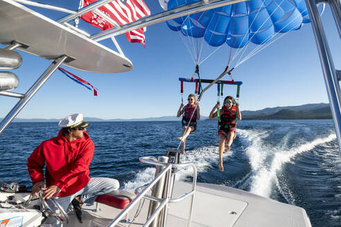 Der Kapitän lächelt, als er zwei Frauen zum Parasailing schickt. - CAVF96652