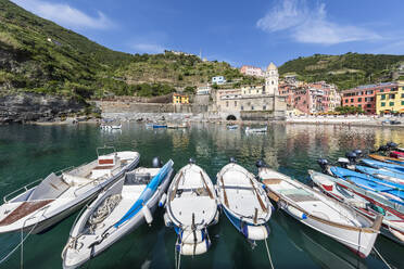 Italy, Liguria, Vernazza, Boats moored at edge of coastal town along Cinque Terre - FOF13544
