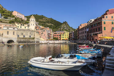 Italy, Liguria, Vernazza, Edge of coastal town along Cinque Terre with boats moored in foreground - FOF13554