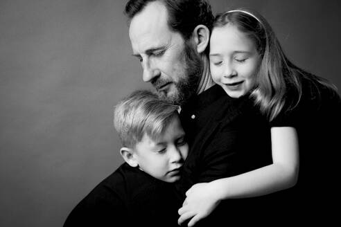 Vater und Kinder umarmen sich mit geschlossenen Augen - GMLF01328