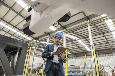 Ingenieur mit Schutzhelm und Tablet-PC in einer Fabrik - JCCMF09668