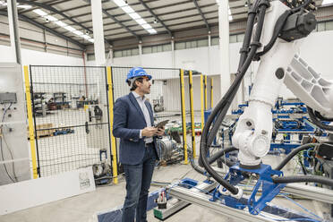 Ingenieur mit Schutzhelm, stehend mit digitalem Tablet-PC in einer Fabrik - JCCMF09672