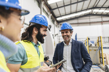 Glücklicher Ingenieur mit Kollegen in der Fabrik stehend - JCCMF09684