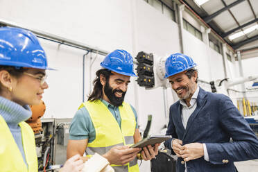 Zufriedener Ingenieur mit Kollegen bei der Nutzung eines Tablet-PCs in der Fabrik - JCCMF09685