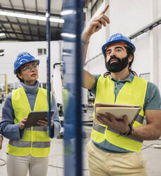 Engineer gesturing colleague in factory - JCCMF09698