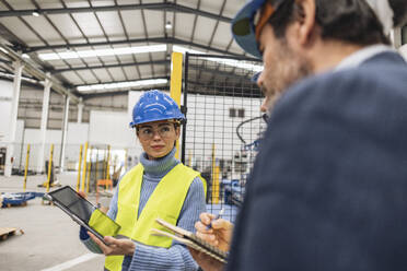 Engineer showing colleagues through tablet PC in factory - JCCMF09703