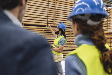 Ingenieur bei der Qualitätskontrolle von Brettern mit Kollegen im Vordergrund - JCCMF09706