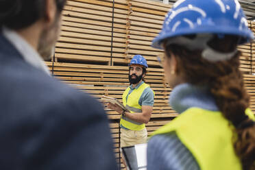 Ingenieur stehend vor einem Stapel Bretter mit Kollegen im Vordergrund - JCCMF09707