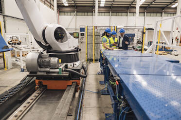 Ingenieur mit Kollegen, die in der Roboterfabrik arbeiten - JCCMF09713